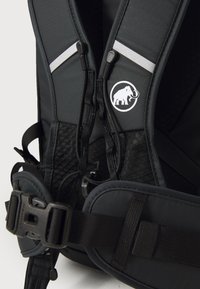 Svart ryggsekk med polstrede skulderstropper, en teksturert mesh-back, justerbare spenner og et sirkulært logo som viser en elefant.