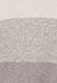 Strickstoff in drei horizontalen Streifen: oben beige, in der Mitte hellgrau, unten dunkelgrau. Weiche Textur, einheitliches Muster, keine sichtbaren Hardware.