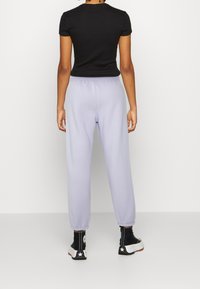 Černý krátký rukáv top spárovaný s levandulovými tepláky. Tepláky mají elastický pas a zúžené kotníky. Černé vysoké boty s bílými akcenty.