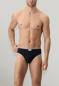 Slip blu navy realizzato in tessuto liscio, con una scollatura bassa, un cinturino ampio e un'etichetta con logo al centro anteriore.