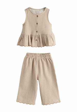 Bēša un balta svītrainu bezroku tops ar pogām un volānu malu, kopā ar atbilstošām elastīgas jostasvietas kapri biksēm, abām ar viļņotām malām.