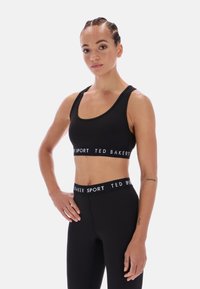 Juodas sportinis trumpas topas ir aukštai pakėlė kelnaitės su baltu "TED BAKER SPORT" prekiniu ženklu. Lygus audinys, prigludęs dizainas ir plačios petnešos.