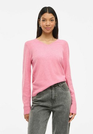 Roze v-hals trui met lange mouwen en ribgebreide manchetten, gecombineerd met grijs gestreepte jeans. Zachte textuur, ontspannen pasvorm, toont een casual stijl.