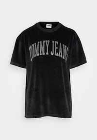 Camisa de terciopelo negra de manga corta con "TOMMY JEANS" en brillantes strass en el pecho, cuello redondo y corte relajado.