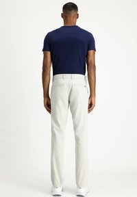 Camisa de manga corta azul marino combinada con pantalones gris claro. Los pantalones tienen bolsillos traseros y un diseño de pierna recta. Unos zapatos blancos completan el conjunto.