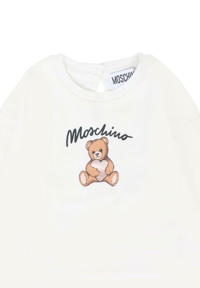 Witte sweatshirt met een grafisch ontwerp van een bruine teddybeer die een hart vasthoudt, met daarboven in zwarte cursieve tekst "Moschino" gedrukt.