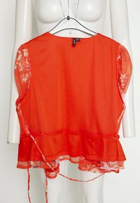 Top vermelho sem mangas com mangas de chiffon floral, bainha com babados e laços na cintura. Tecido suave com uma textura macia.