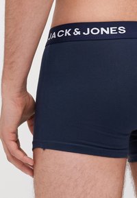 Navy blue boxer briefs made of soft fabric featuring a wide elastic waistband with "JACK & JONES" logo in white, smooth texture.