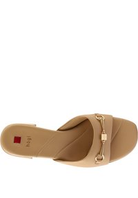 Beige platte slipper met een kruisbandontwerp, gemaakt van soepel leer, goudkleurige decoratieve hardware en een gevoerd voetbed.