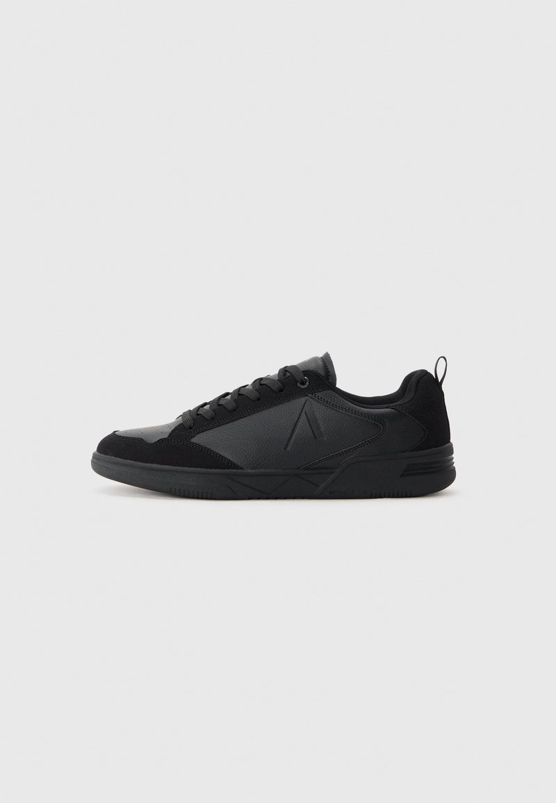 Schwarze tiefe Sneaker mit Schnürverschluss, strukturierten und glatten Paneelen sowie einem Zugschlaufen am Fersenbereich auf einem schlichten hellen Hintergrund.