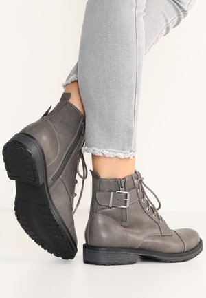Szare skórzane botki za kostkę z sznurowaniem z przodu, zamkiem błyskawicznym po boku i metalowym detalem w postaci klamry. Teksturowana gumowa podeszwa zapewniająca przyczepność.