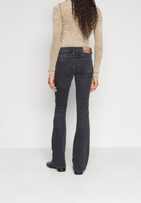 Ciemnoszare dzwony o subtelnym wzorze i dwóch tylnych kieszeniach. Noszone z długim, dopasowanym topem w jasnym beżu.