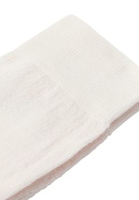 Vit bomullssocka med ribbat topp, som har en mjuk textur och slät yta, sträcker sig mot tån med en rundad form.