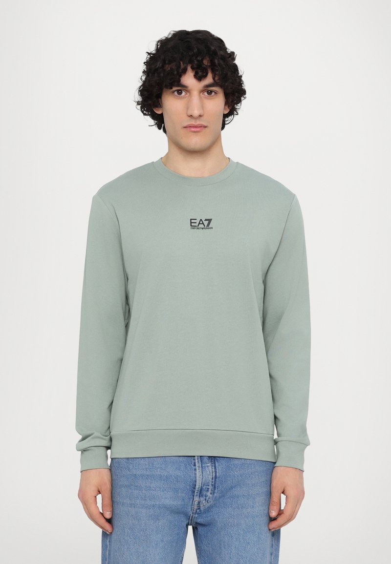 Felpa verde chiaro con maniche lunghe, collo rotondo e piccolo logo EA7 nero sul petto. Tessuto morbido, vestibilità casual e polsini a costine.