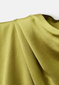 Tela verde oliva dispuesta en suaves capas, de textura suave, con un sutil brillo que resalta sus delicados pliegues y contornos.