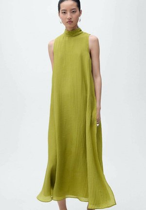 Robe longue sans manches en tissu léger et froissé de couleur verte. Col montant, coupe décontractée et forme fluide avec un ourlet qui bouge doucement.