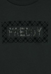 Maglietta nera con la parola "FREDDY" in borchie argentate, circondata da un motivo geometrico testurizzato in una tonalità di nero più scura.