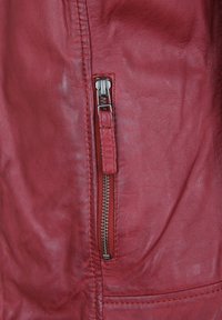 Rote Lederjacke mit seitlichem Reißverschluss aus Metall, detailgenauer Nahtführung und strukturiertem Finish.