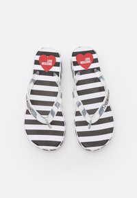 Infradito a righe bianche e nere con soletta testurizzata e cinturini trasparenti; presenta un cuore rosso con il testo "LOVE MOSCHINO".