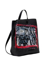 Musta nahkarepussa on suorakaiteen muotoinen muotoilu, jossa on värikäs graafinen kuvio ja merkki, jossa lukee "Noir sur blanc". Säädettävät hihnat.