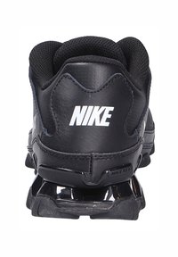 Μαύρα αθλητικά παπούτσια Nike με κομψό σχεδιασμό, συνθετικό υλικό, πάνω μέρος από δίχτυ και ορατή απορρόφηση κραδασμών στη φτέρνα. Λογότυπο "NIKE" στο πίσω μέρος.