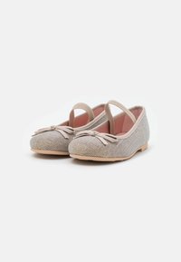 Ballerine in beige chiaro con tomaia in tessuto strutturato, fasce elastiche e un piccolo fiocco sulla punta. Suola piatta in gomma per il comfort.