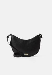 Černá kožená crossbody taška s zakřiveným tvarem, texturovaným povrchem a zlatým kovovým logem jako akcentem. Nastavitelný popruh pro všestrannost.