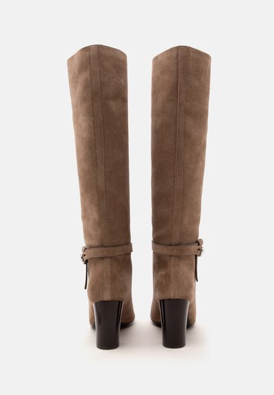 Paire de bottes hautes en daim marron avec talons carrés et brides à la cheville, vues de dos sur fond blanc.
