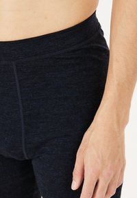 Navy Stretch-Leggings aus einem weichen, strukturierten Stoff mit einem breiten Bund und subtilen, gestickten Details an den Seitennähten.