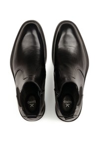 Bottines en cuir noir avec un design épuré, des bouts ronds, des fermetures éclair sur les côtés et un minimum de couture. Doublure intérieure douce pour le confort.