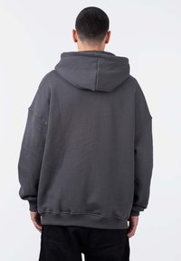 Felpa oversize grigio scuro con un tessuto morbido e testurizzato. Presenta un grande cappuccio, spalle scese e polsini e orlo a costine.