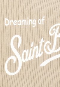 Tessuto beige con trama a costine verticali con testo ricamato in bianco: "Sognando Saint B." Il testo presenta stili corsivo e stampatello.