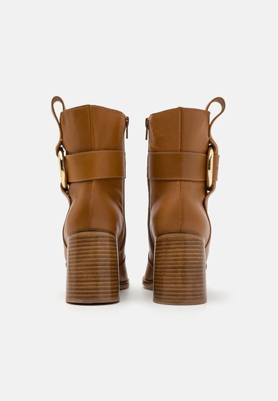 Brune læder ankelstøvler med struktureret design, sideskydere og tykke, riflede blokhæle. Har en bred rem med en gylden accent.