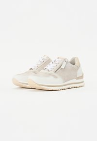 Sneaker con una combinazione di colori beige chiaro e bianco, tessuto testurizzato, dettagli lisci, lacci bianchi e un sottile zip.