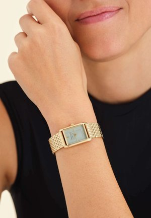 Reloj rectangular en tono dorado con una esfera azul clara y pulsera de malla dorada. Presenta marcadores horarios sencillos y una pequeña corona en la parte superior.