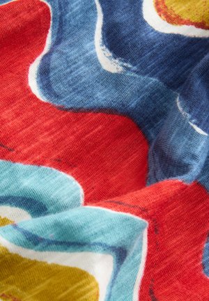 Tejido multicolor con patrones florales abstractos en rojo, azul y amarillo. La textura es suave, con una apariencia ligeramente tejida.