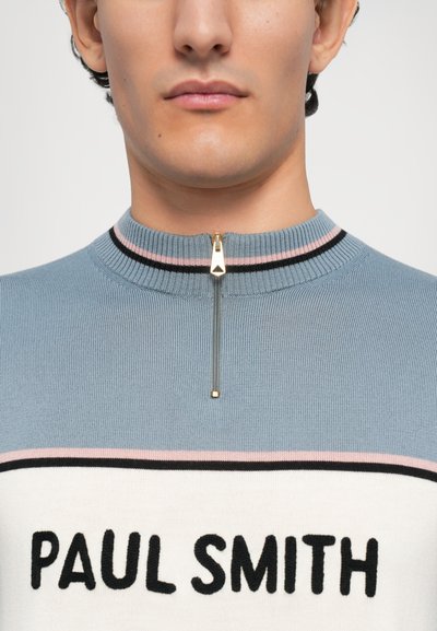 Suéter de punto azul claro con cuello alto, con una cremallera dorada, rayas negras y rosas, y "PAUL SMITH" en letras negras en negrita.