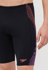 Čierne plavky s priliehavým strihom, so štýlovým multikolorovým vzorom v ružovej a fialovej farbe na boku a ružovým logom Speedo.