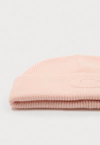 Pink knitted beanie hat with a ribbed texture and a folded cuff. Features a subtle logo detail on the cuff, lightweight material.