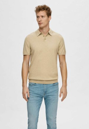 Polo de punto beige con mangas cortas, tapeta de dos botones y dobladillo acanalado, combinado con unos vaqueros azul claro. Textura suave, ajuste casual.