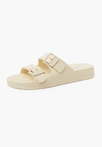 Sandalia de goma beige tipo slide con dos correas ajustables con hebillas, superficie texturizada y suela plana con un patrón de relieve para mayor agarre.
