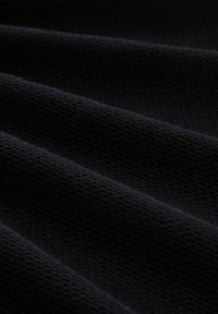 Schwarzer Textilstoff mit einem gerippten Muster, das weiche, leicht erhobene Flächen präsentiert, die einen wellenartigen Effekt erzeugen.