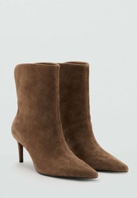 Botines de ante marrón con punta afilada y tacón delgado. Textura suave con diseño ajustado, sin herrajes ni detalles visibles.