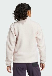 Jasnoróżowy polarowy sweter z wysokim kołnierzem, fakturowaną powierzchnią i ściśniętymi mankietami. Tył prezentuje luźny krój i prosty design.