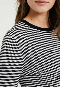 Maglione a righe bianche e nere con scollo rotondo, motivo lavorato a maglia e silhouette aderente.