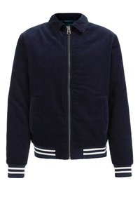 Marinblå kordjacka med ståkrage, framzipper, två sidofickor och randiga ribbade muddar och nederkant. Texturerad tyg med regular fit.