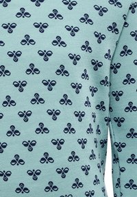 Hellblauer Stoff mit wiederholtem dunkelblauen Bienenmuster, das geometrische Akzente und eine weiche Textur aufweist, wobei aufwändige Details hervorgehoben werden.