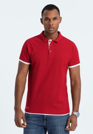 Camisa polo roja de algodón con detalles blancos en el collar y las mangas. Presenta una tapeta de tres botones y un dobladillo recto.