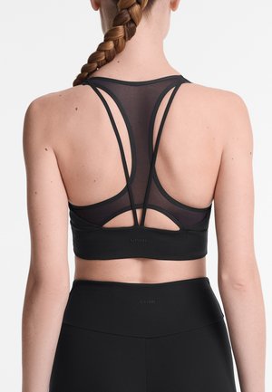 Soutien-gorge de sport noir avec un dos en maille, présentant des bretelles fines et croisées ainsi qu'une bande élastique lisse. Logo simple à l'ourlet.