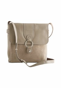 Beige læder- og ruskinds crossover taske med flaplukning, rund metalaccent og justerbar rem. Glatte og strukturerede overflader.